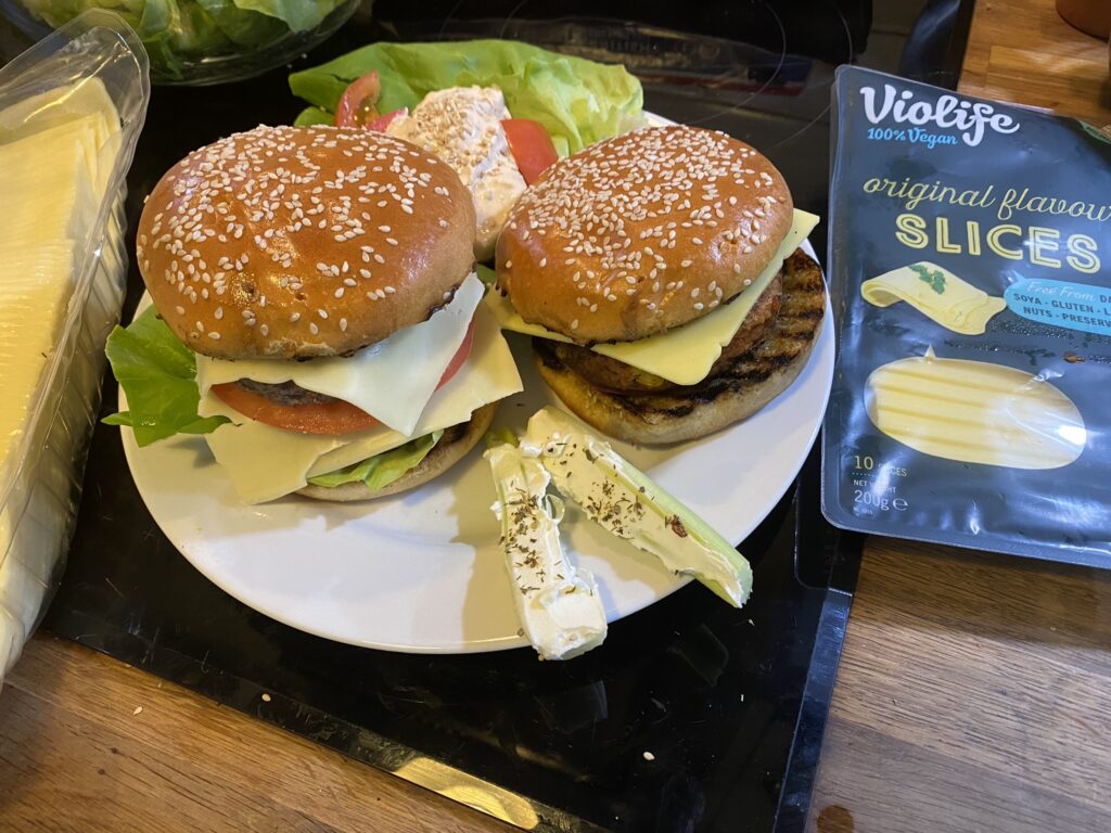 Burger on the left a double quarter pounder with cheese slice. On the right a vegan burger with a slice of Violife cheese