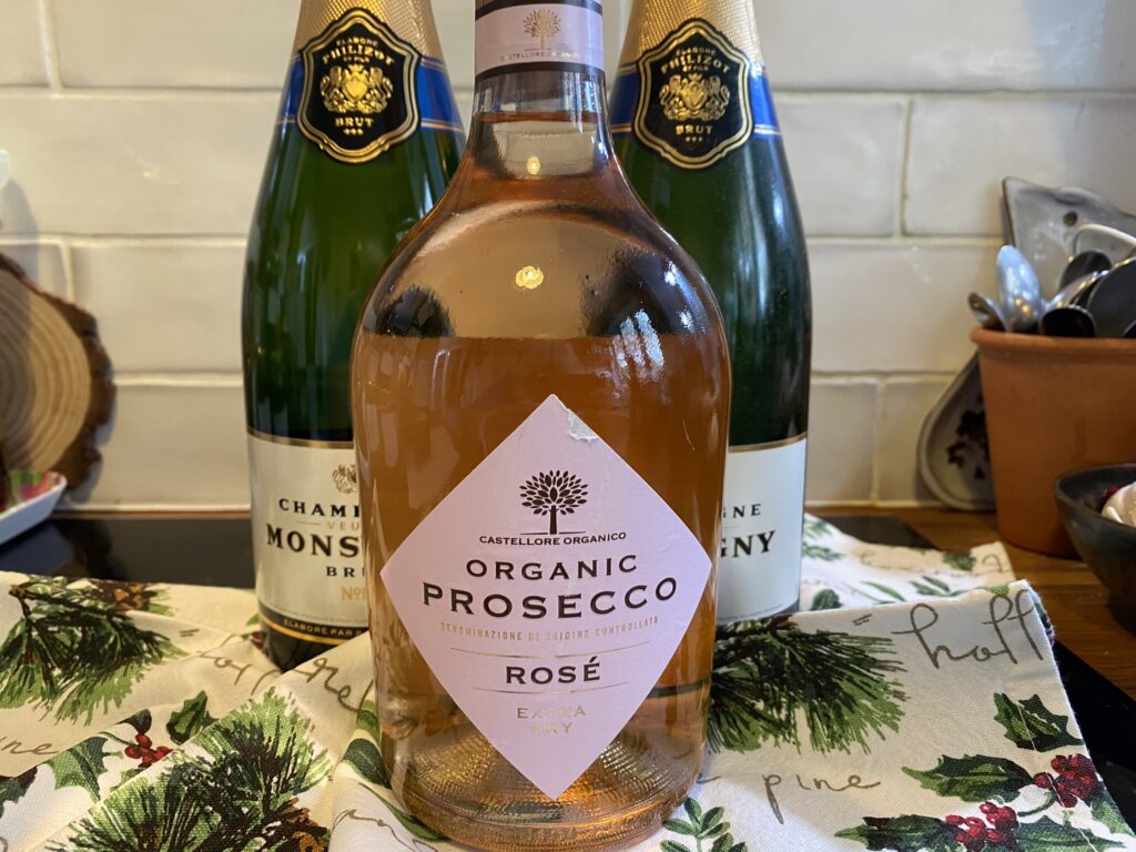 Pink Prosecco in front of two bottles of champagne
