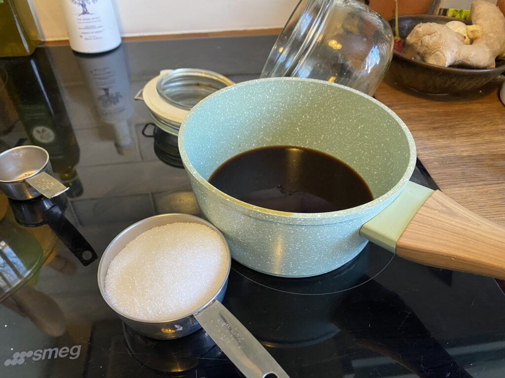 Green pot with cognac from soaking and a cup of sugar